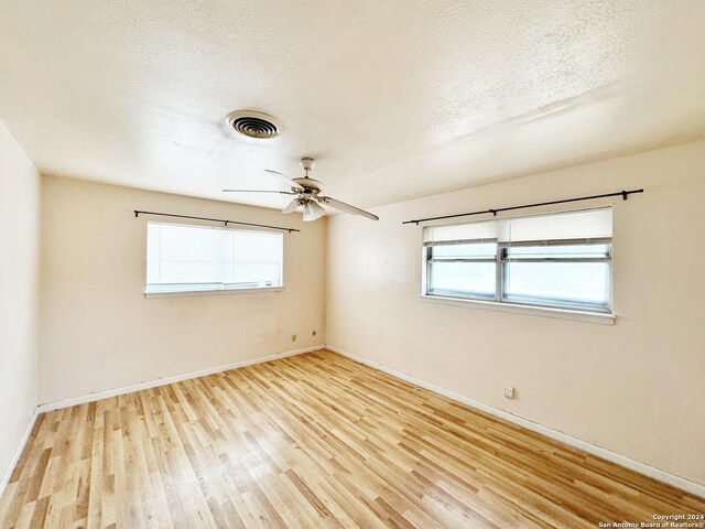 spare room featuring light wood-type flooring, ceiling fan, and a textured ceiling