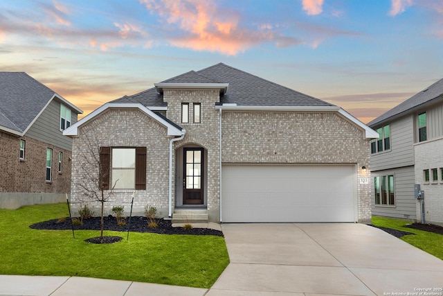 view of front of property with a garage, a yard, concrete driveway, and brick siding