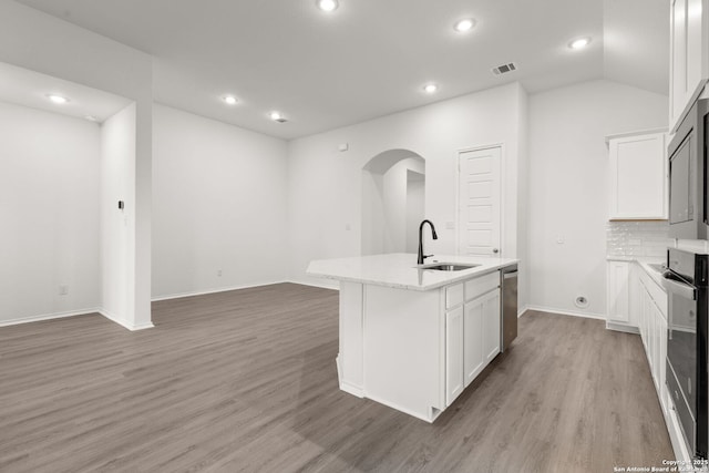 kitchen with stainless steel dishwasher, a sink, oven, and light wood-style floors