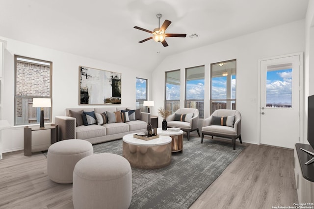 living area featuring lofted ceiling, a ceiling fan, visible vents, and wood finished floors