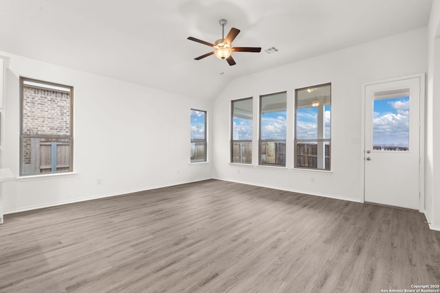 unfurnished living room featuring baseboards, visible vents, a ceiling fan, wood finished floors, and vaulted ceiling