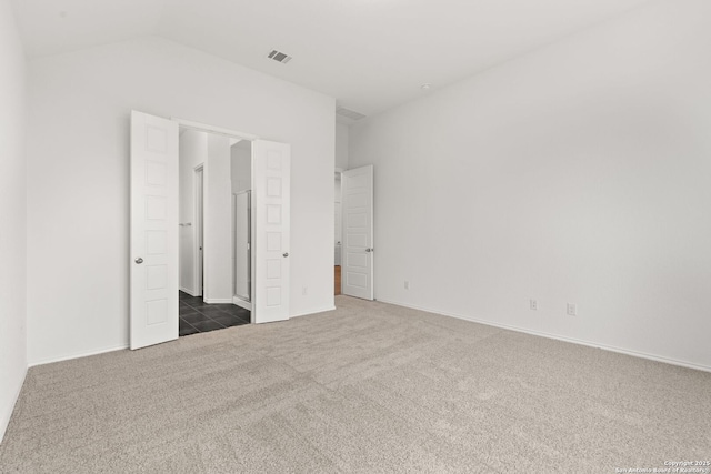 unfurnished bedroom with lofted ceiling, dark colored carpet, visible vents, and baseboards