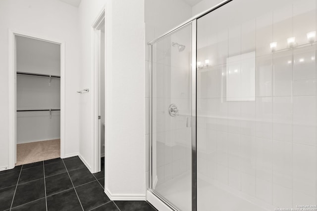 bathroom featuring a stall shower, a spacious closet, baseboards, and tile patterned floors