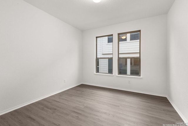 empty room featuring wood finished floors and baseboards