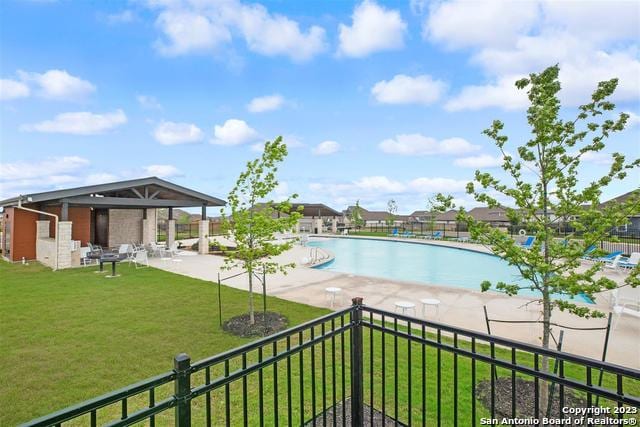 pool with fence, a patio, and a yard