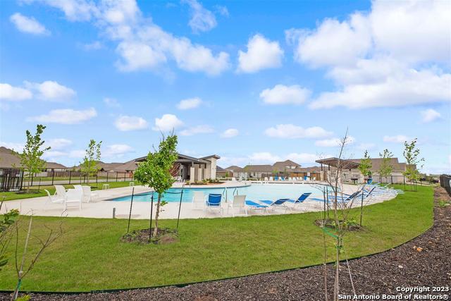 community pool featuring a yard, a patio area, and fence