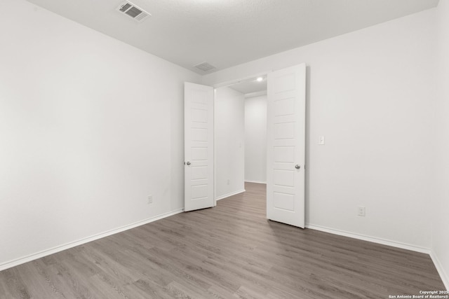 spare room featuring visible vents, baseboards, and wood finished floors