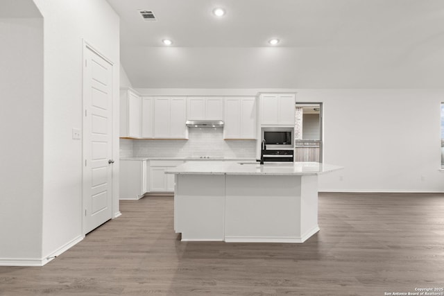 kitchen with under cabinet range hood, white cabinetry, built in microwave, and tasteful backsplash