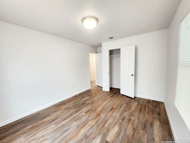 unfurnished bedroom with a closet and dark hardwood / wood-style flooring