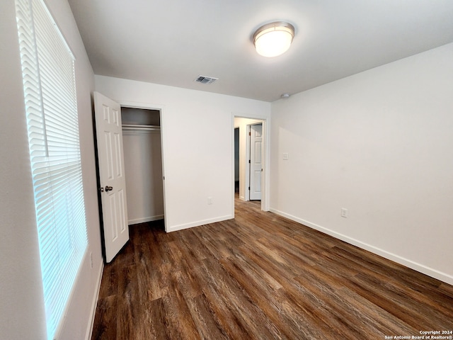 unfurnished bedroom featuring dark hardwood / wood-style floors and a closet