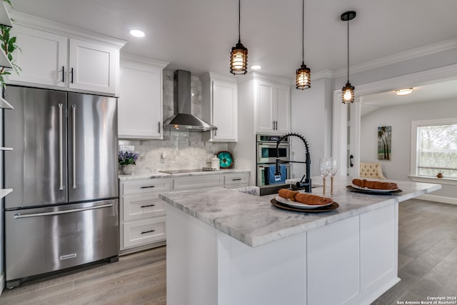 kitchen featuring a kitchen island with sink, white cabinetry, light hardwood / wood-style flooring, stainless steel appliances, and wall chimney range hood