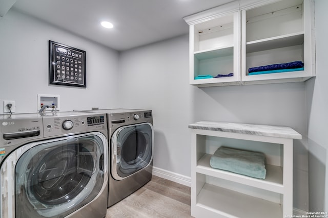 laundry room with washing machine and dryer and light wood-type flooring