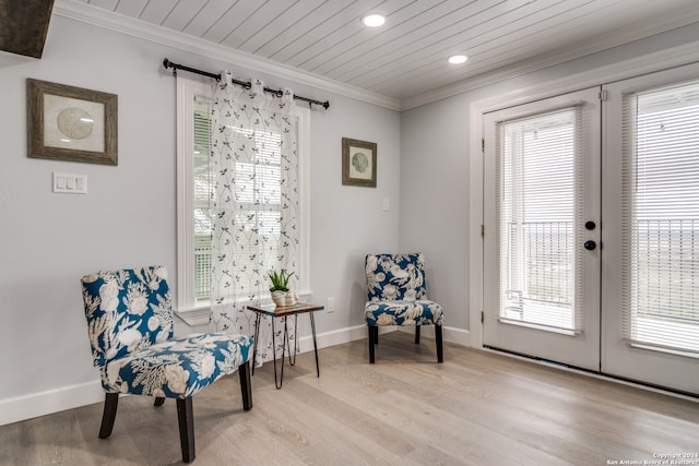 living area featuring ornamental molding, light hardwood / wood-style flooring, and a healthy amount of sunlight