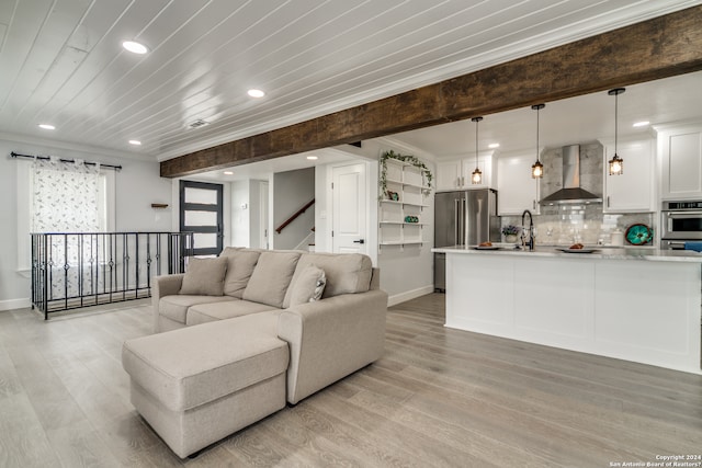 living room featuring light wood-type flooring, wood ceiling, crown molding, and sink