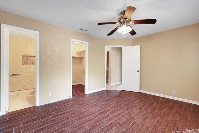 unfurnished bedroom with ceiling fan, a textured ceiling, a closet, a spacious closet, and ensuite bathroom