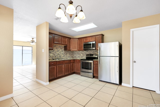 kitchen with tasteful backsplash, sink, ceiling fan with notable chandelier, hanging light fixtures, and stainless steel appliances