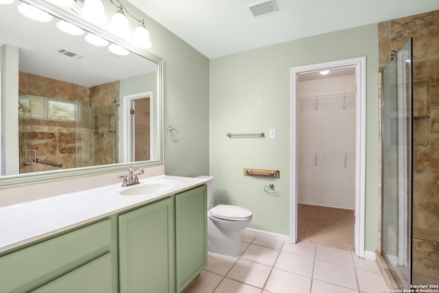 bathroom featuring vanity, toilet, a shower with shower door, and tile patterned flooring