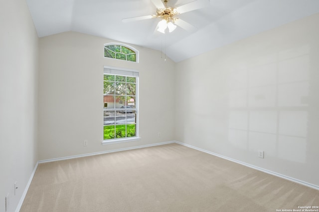 empty room featuring lofted ceiling, ceiling fan, and light colored carpet