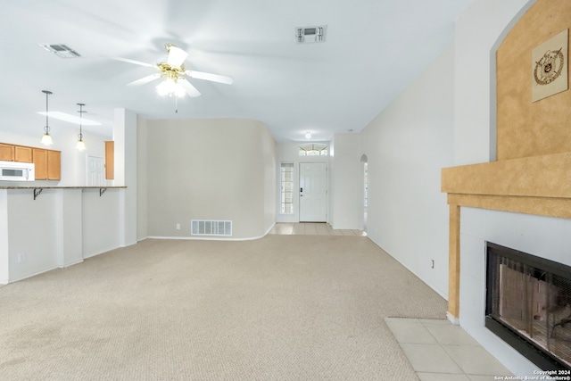 unfurnished living room with light colored carpet and ceiling fan