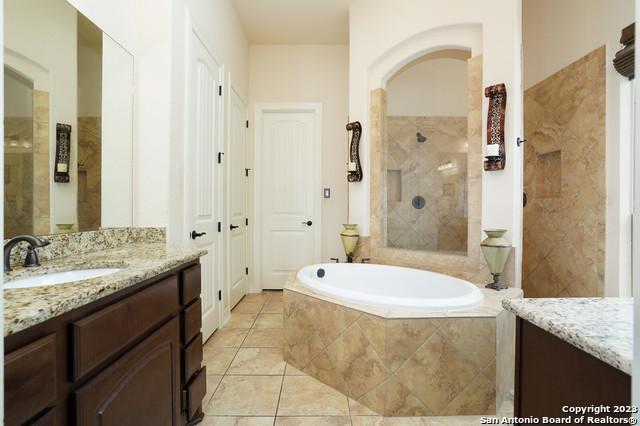 full bathroom with a garden tub, a tile shower, vanity, and tile patterned floors