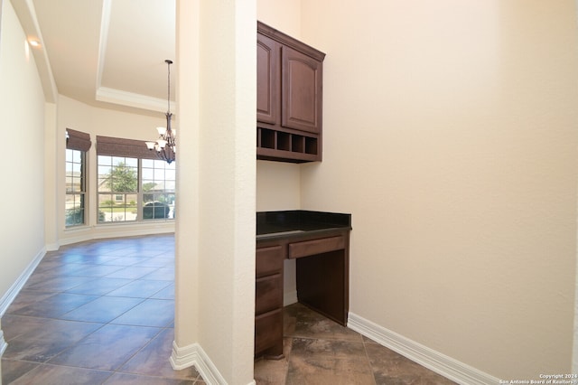 kitchen featuring crown molding, dark tile patterned flooring, a notable chandelier, and hanging light fixtures