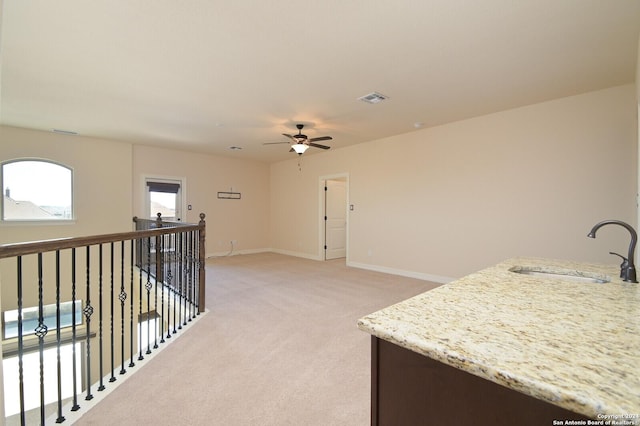 kitchen featuring light colored carpet, a sink, visible vents, baseboards, and light stone countertops