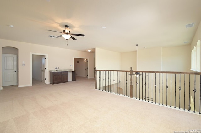 unfurnished room featuring arched walkways, visible vents, ceiling fan, and light carpet