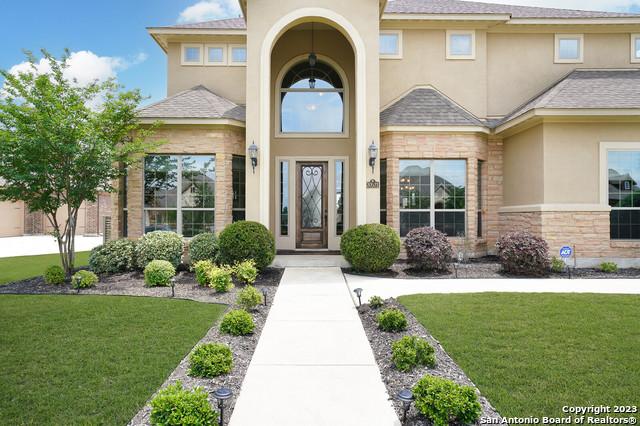 doorway to property featuring stone siding, a yard, and stucco siding