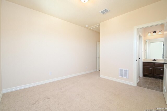 unfurnished bedroom featuring light colored carpet, connected bathroom, and sink