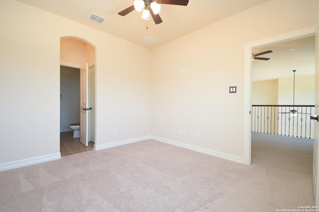 spare room featuring carpet floors, baseboards, visible vents, and arched walkways