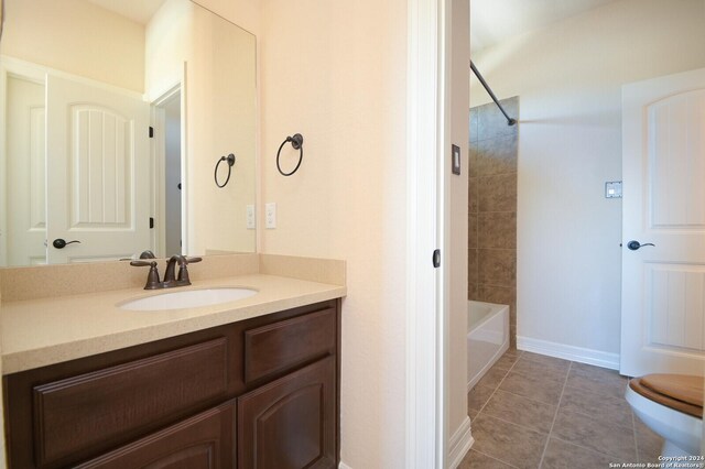 full bathroom featuring vanity, tiled shower / bath, tile patterned floors, and toilet