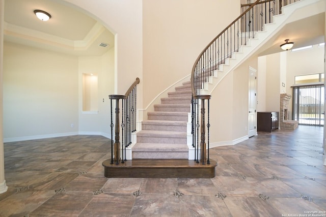 stairway with a towering ceiling, visible vents, and baseboards