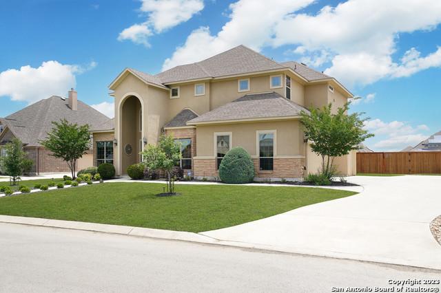 view of front facade with fence, concrete driveway, stone siding, stucco siding, and a front yard