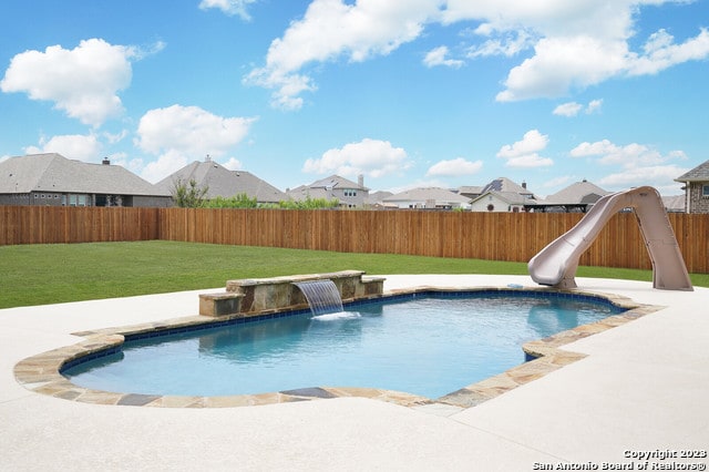 view of pool featuring a water slide, a patio area, a lawn, and pool water feature