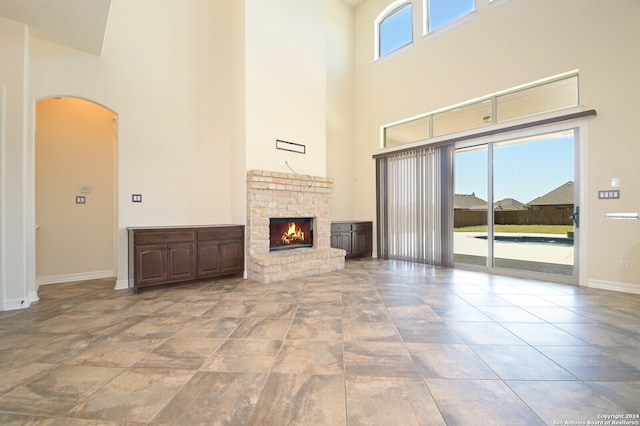 unfurnished living room with a healthy amount of sunlight, a high ceiling, and a stone fireplace