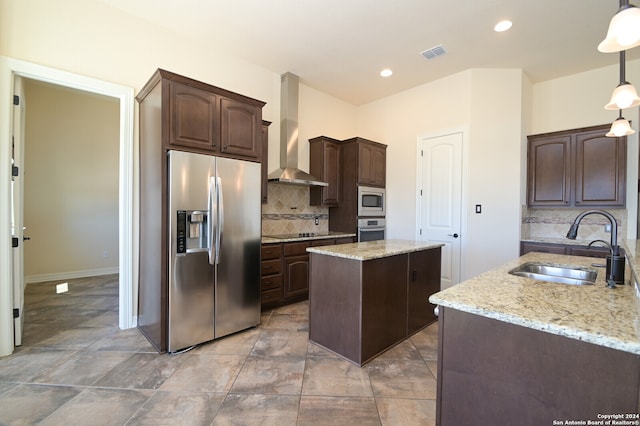 kitchen featuring a kitchen island, pendant lighting, appliances with stainless steel finishes, sink, and wall chimney range hood