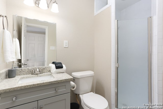 bathroom featuring lofted ceiling, walk in shower, toilet, and vanity