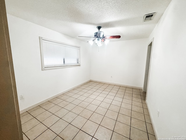 tiled spare room with a textured ceiling and ceiling fan