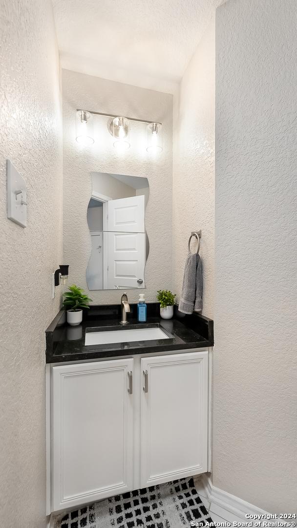 bathroom with a textured wall and vanity