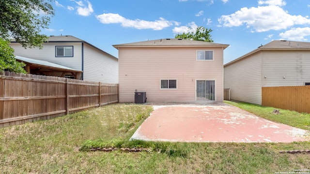 back of house with central air condition unit, a lawn, and a patio area