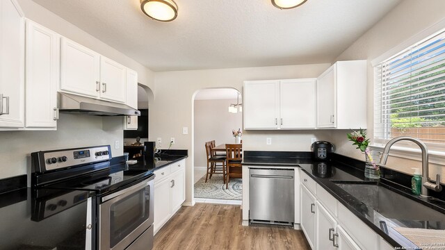 kitchen with light wood-type flooring, white cabinets, appliances with stainless steel finishes, and sink