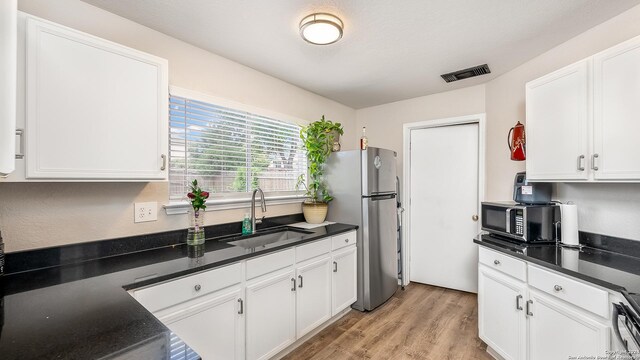 kitchen featuring stainless steel refrigerator, sink, white cabinetry, and light hardwood / wood-style floors