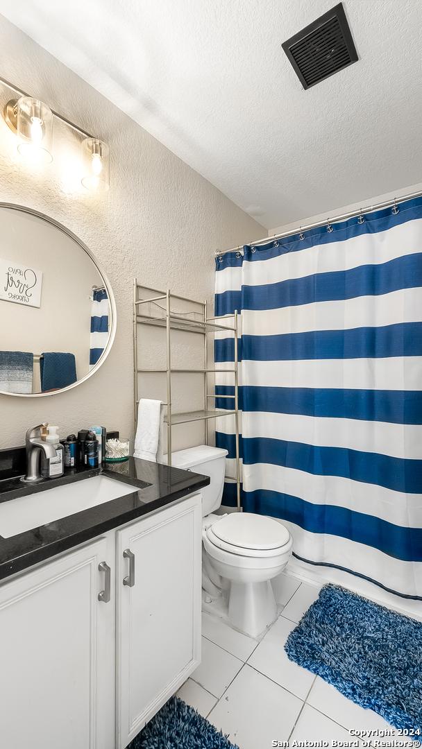 bathroom featuring tile patterned flooring, toilet, a textured ceiling, and vanity