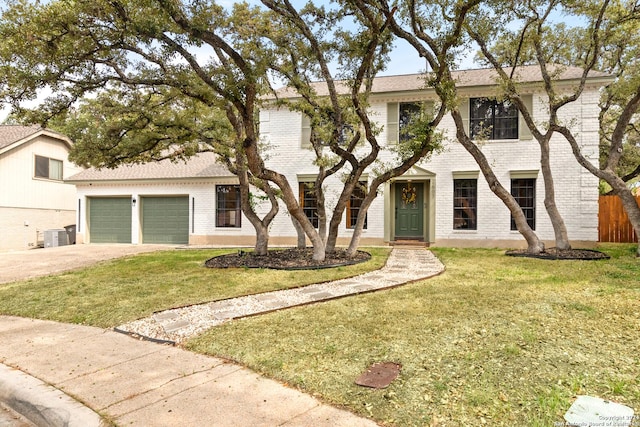 colonial inspired home with an attached garage, driveway, a front yard, and brick siding