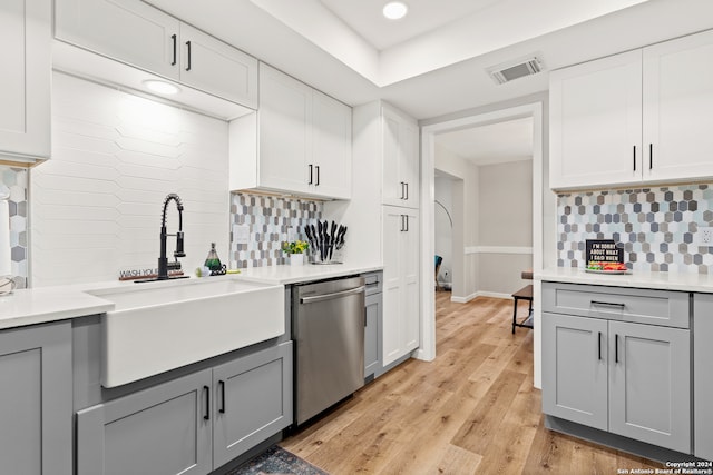 kitchen with sink, tasteful backsplash, gray cabinets, stainless steel dishwasher, and light hardwood / wood-style flooring