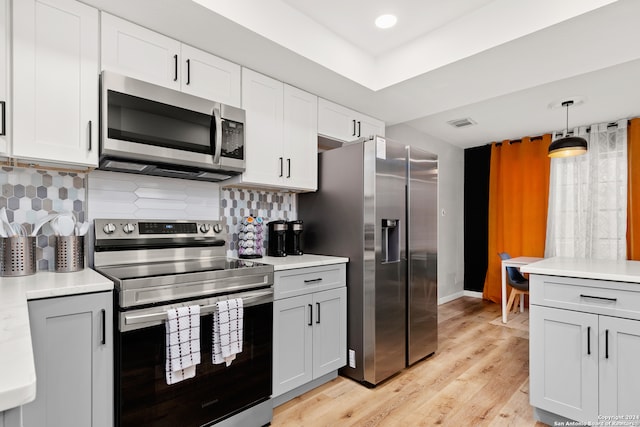 kitchen with stainless steel appliances, light hardwood / wood-style floors, tasteful backsplash, hanging light fixtures, and white cabinets