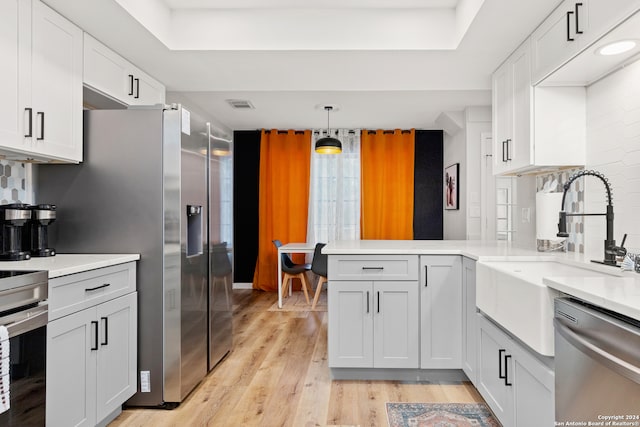 kitchen with stainless steel appliances, white cabinetry, light wood-type flooring, and kitchen peninsula