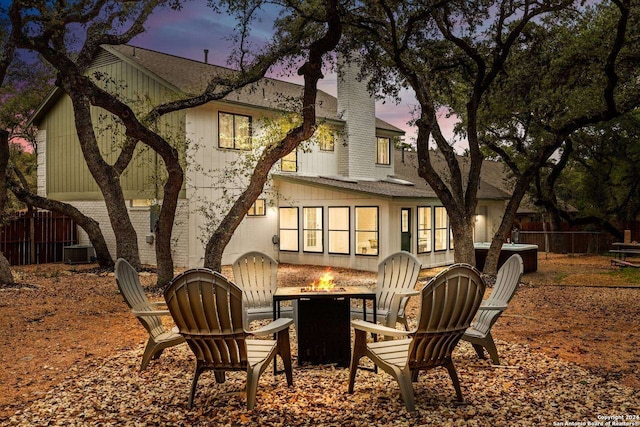 back of property featuring central air condition unit, a fire pit, a shingled roof, fence, and a chimney