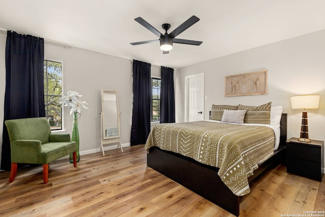 bedroom with ceiling fan, multiple windows, and light hardwood / wood-style floors