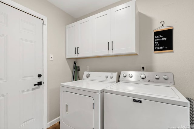 clothes washing area featuring cabinets and separate washer and dryer